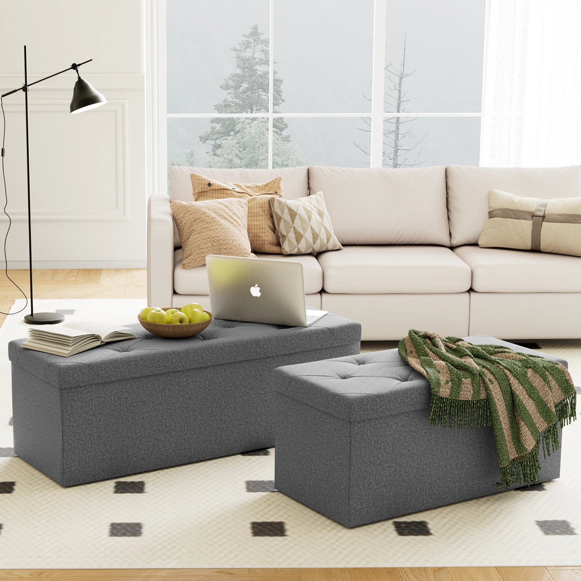 Living room with a beige sectional sofa, gray ottomans, and a laptop on a coffee table.